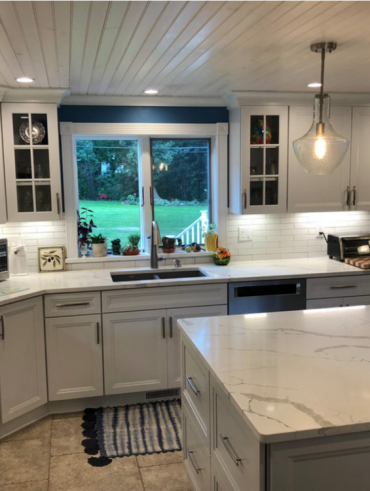 Modern remodeled kitchen with light wood cabinets and marble countertops in Rochester, NY.