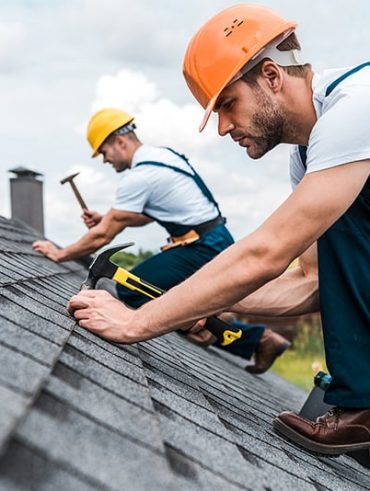 Roof inspector uses drone and tablet on a rooftop covered in solar panels.