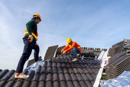 Reliable and Professional Roofing Services in Erie: Your Go-To Roofing Company 1 2 construction workers install new roof construction site electric drill used new roofs with concrete roof tiles concept residential building construction